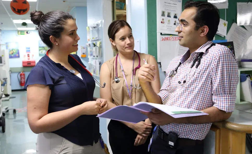 Three doctors in discussion on ward.